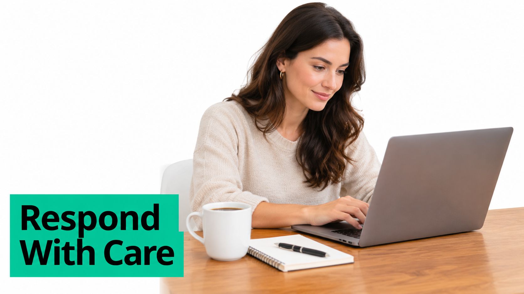 A smiling woman in a beige sweater working on a laptop at a wooden desk with coffee.